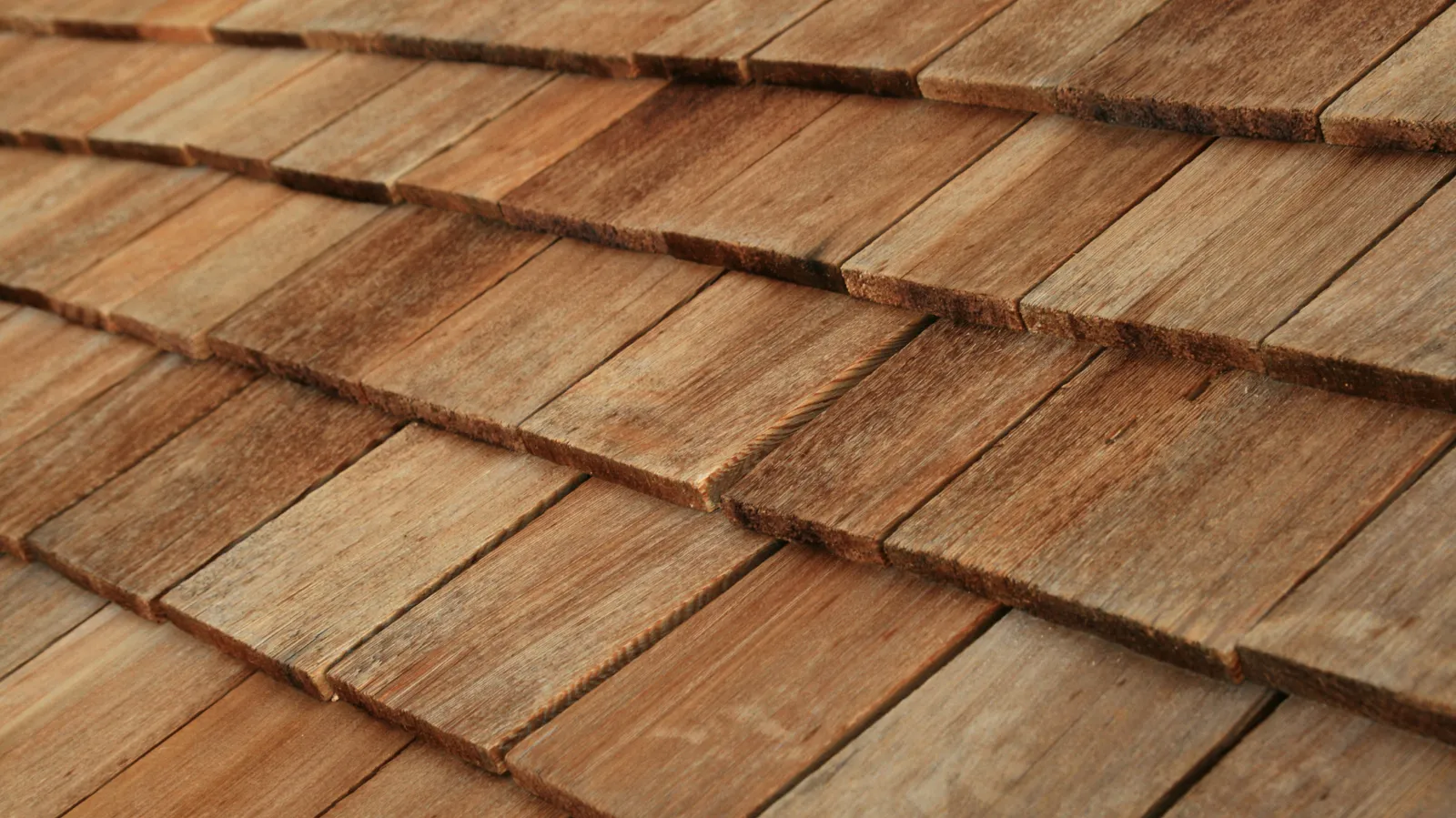 Overlapping courses of warm brown toned cedar shingles